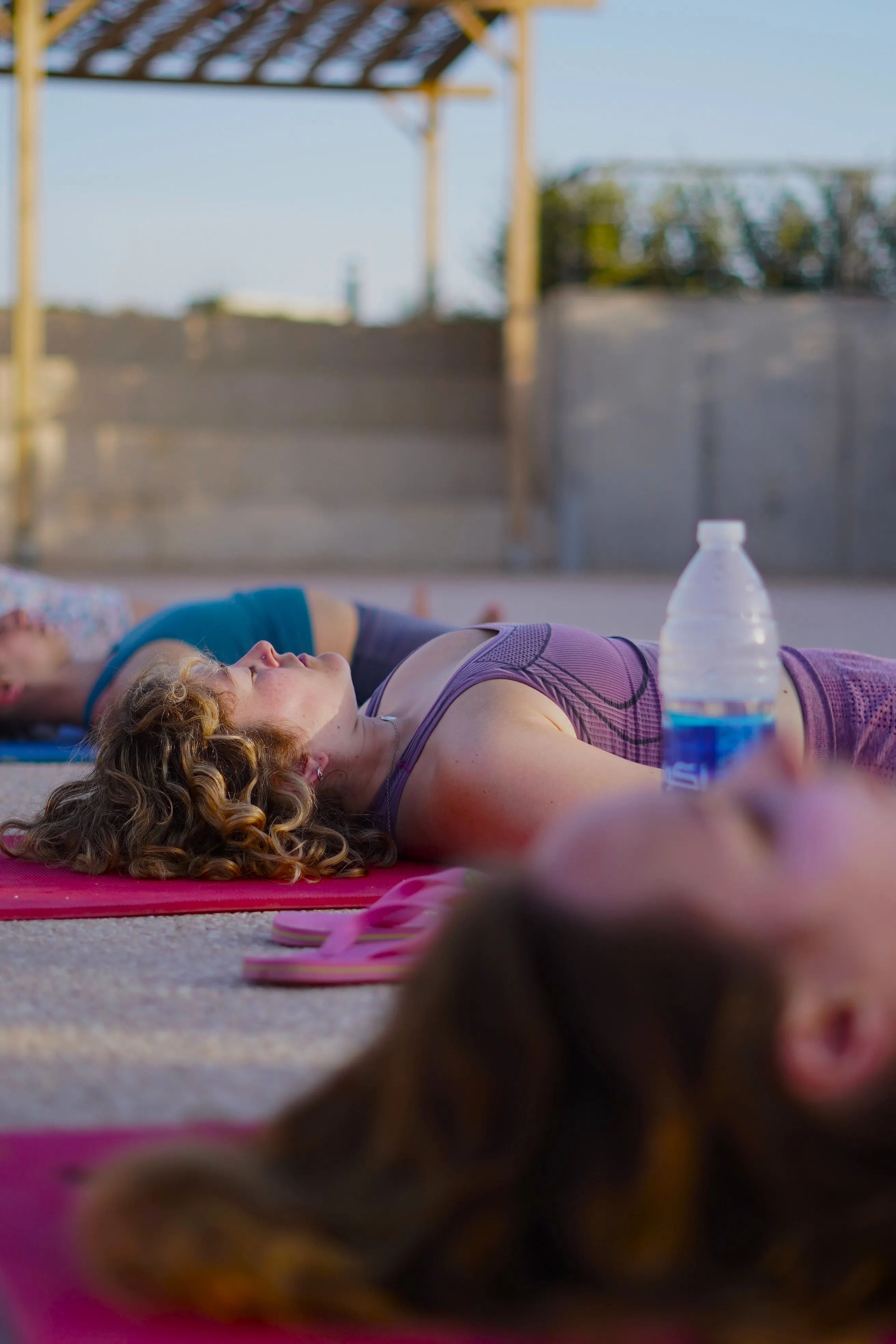 People lying on mats outdoors, possibly during a relaxation or meditation session.