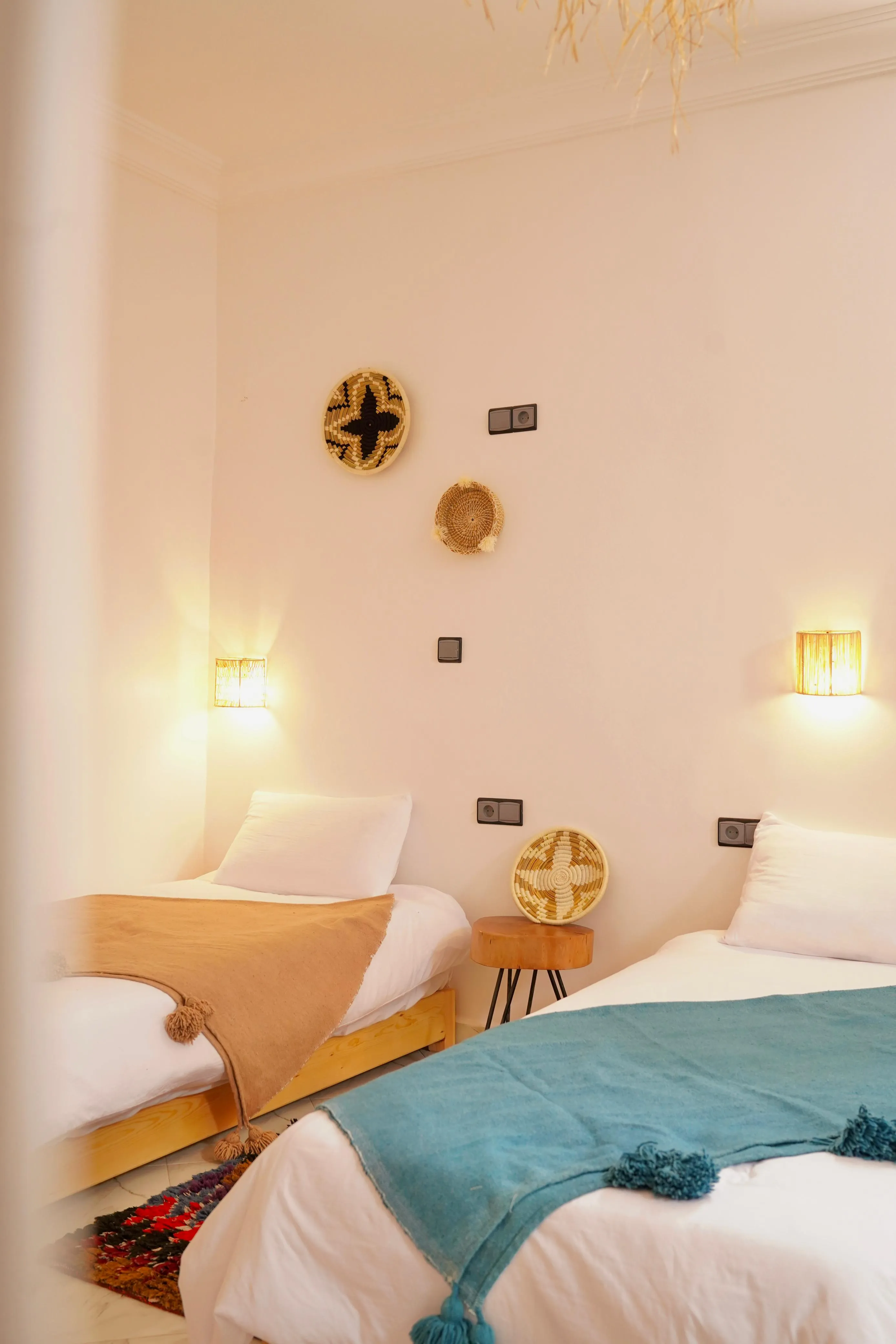 Bedroom with two single beds, one with a brown blanket, the other with a teal blanket and wall decor.