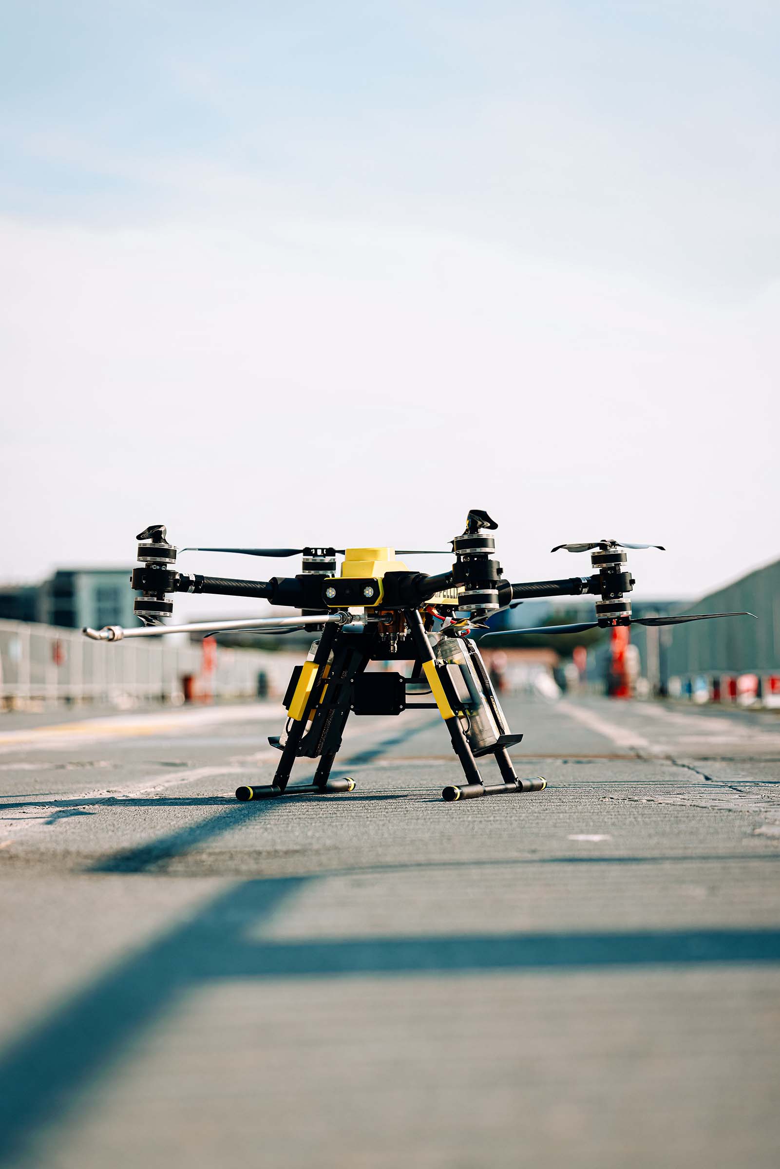 Close-up of a yellow and black quadcopter drone on a concrete runway.