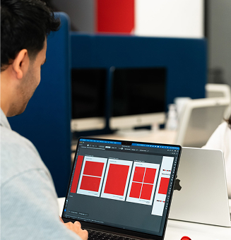 Hombre trabajando en una computadora portátil con múltiples diseños de diagramas rojos en la pantalla.