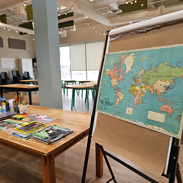 Classroom with a world map on an easel and art supplies on a wooden table.