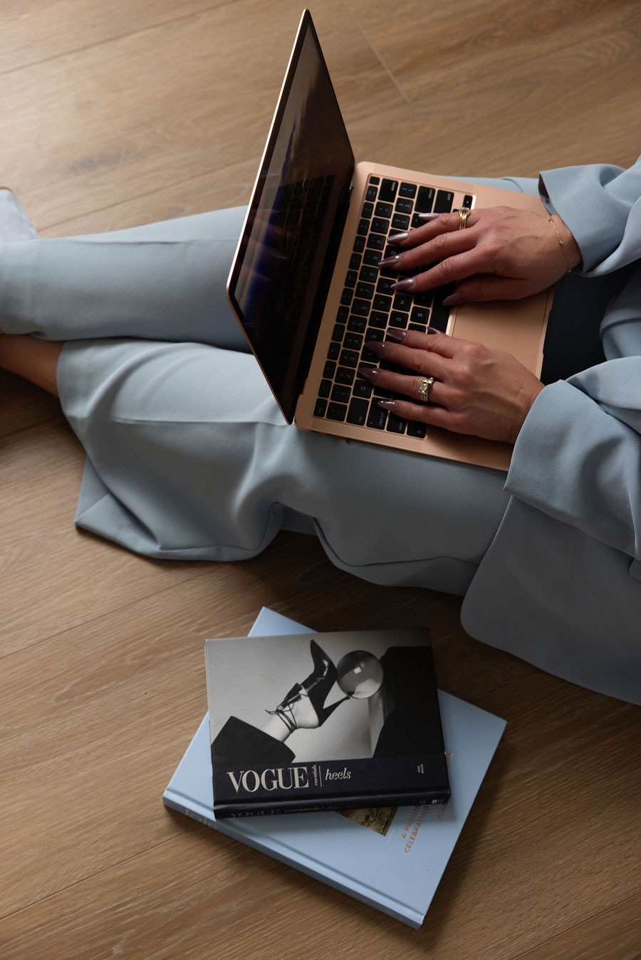 Person working on a laptop while seated on the floor in light blue professional clothing
