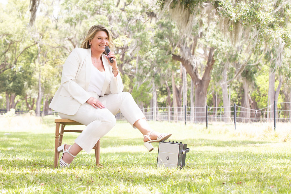 Leadership speaker Tamiko McGurk holding a microphone while seated outdoors