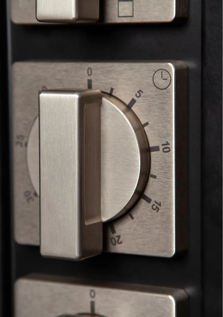 Close-up of a stainless steel timer dial set to 5 minutes on a black background.
