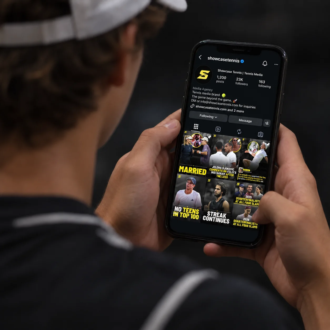 Player in a white cap scrolling the @showcasetennis Instagram profile on his phone
