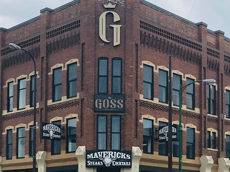 Brick corner building with signs for Mavericks Steaks & Cocktails and a vertical sign for Goss Brewing Co.