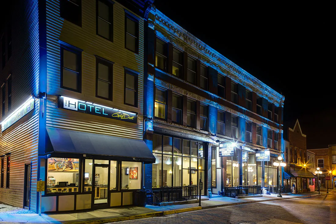 The Hotel Gold Dust building illuminated with blue and white lights at night on a quiet street corner.