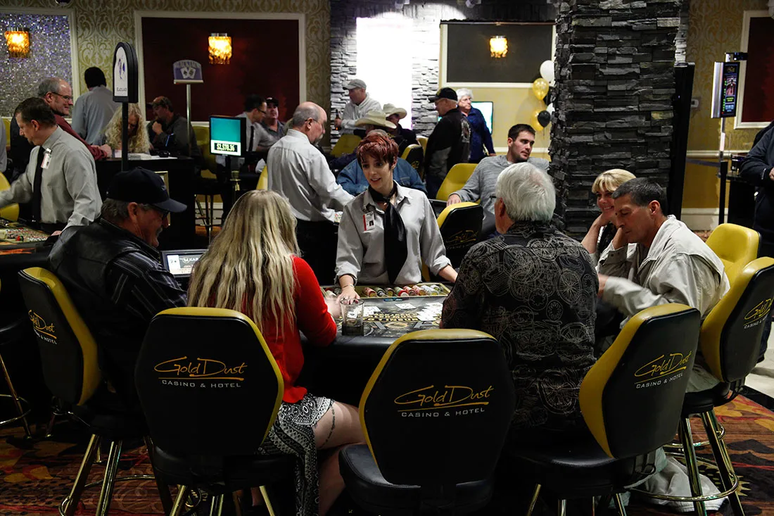 Casino dealer engaging with a group of six players seated around a gaming table at Gold Dust Casino & Hotel.