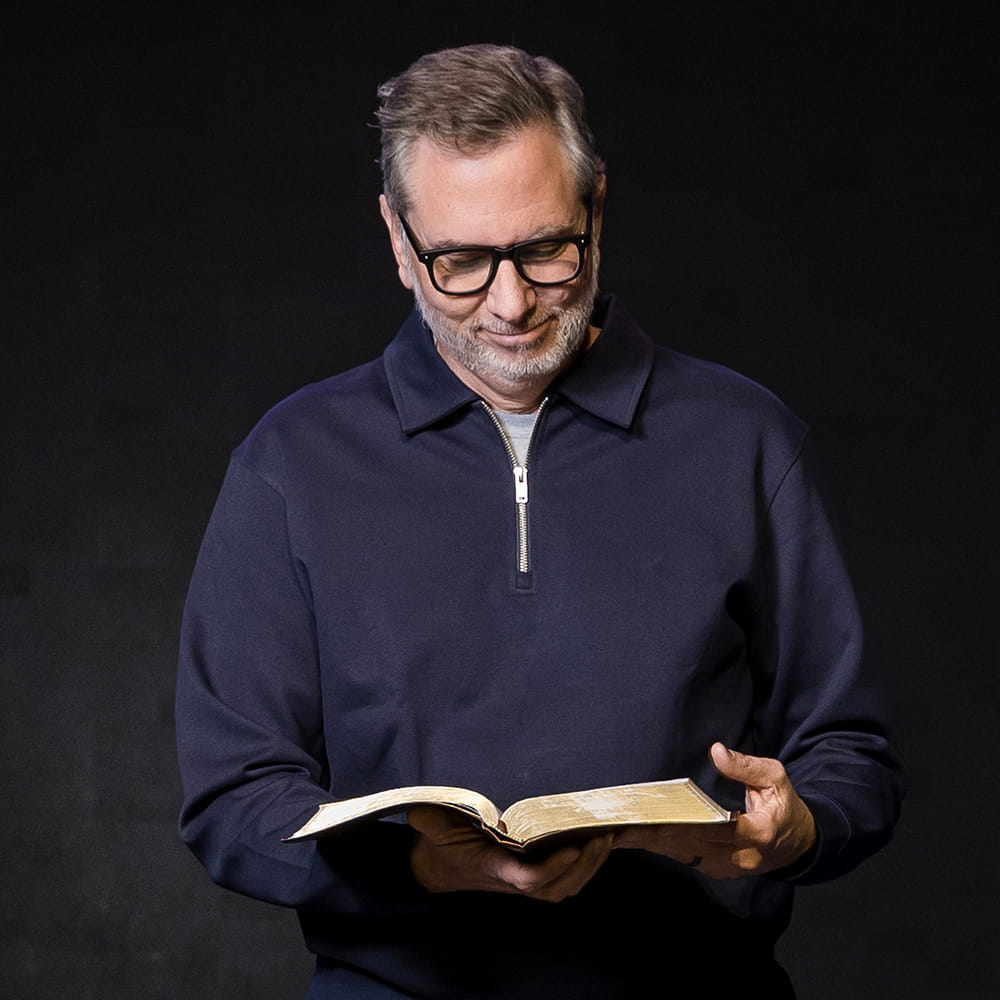Rusty George looking down with a soft smile as he reads his Bible