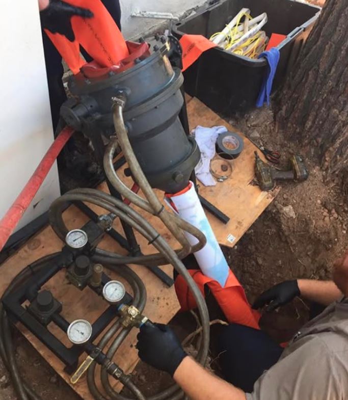 Sump pump repair services in Tucson AZ - technician servicing sump pump with pressure gauge monitoring and replacement parts