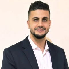 Professional headshot of a bearded man wearing a dark blazer and white shirt.