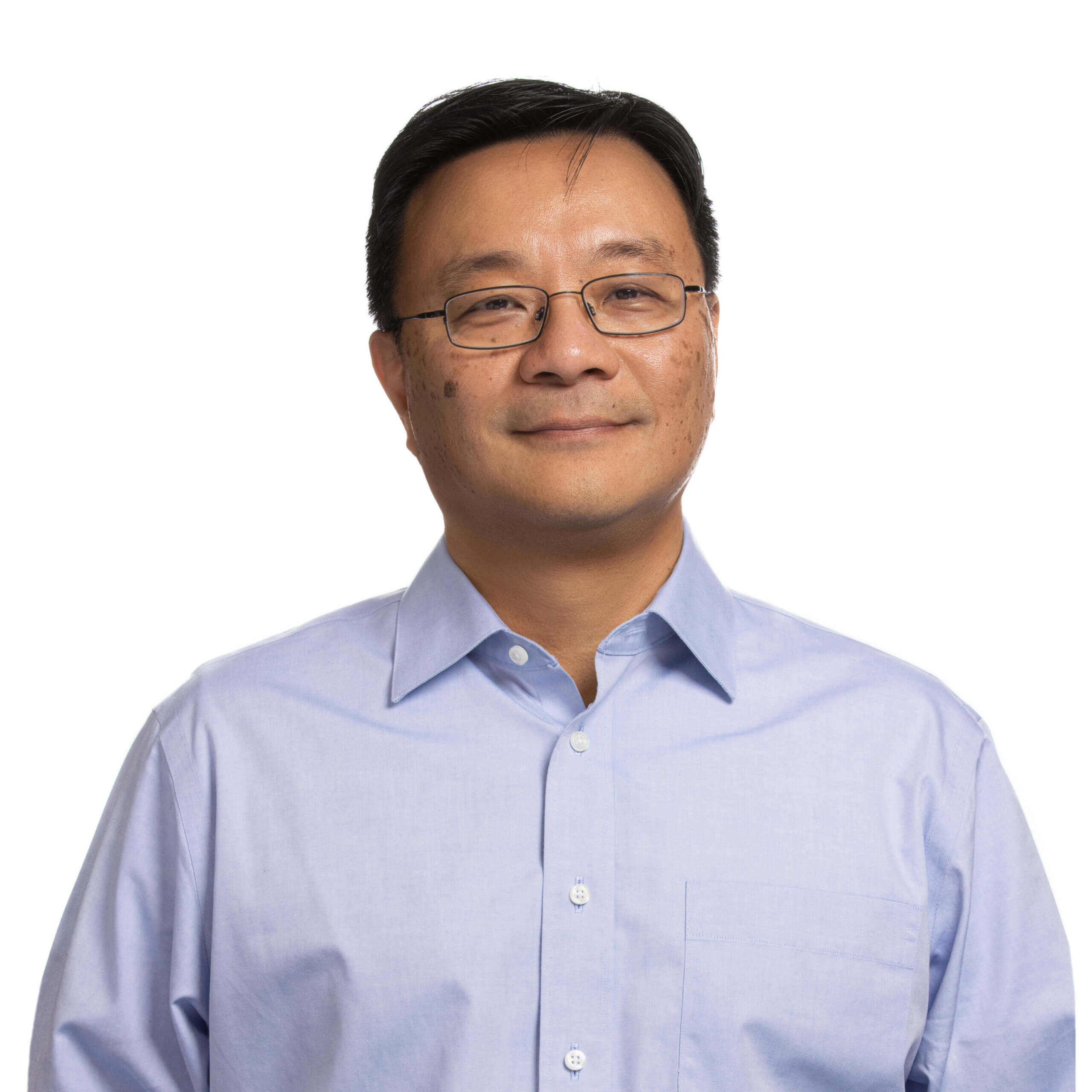 Middle-aged man wearing glasses and light blue button-up shirt against white background