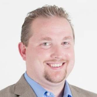 Professional headshot of a smiling man in casual business attire