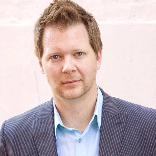 Headshot of man with brown hair wearing navy pinstriped blazer and light blue shirt