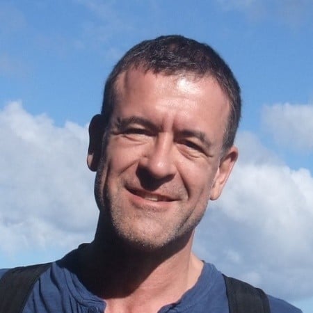Man smiling outdoors on sunny day with blue sky and clouds