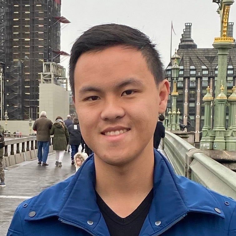 Young man smiling in blue jacket on urban rooftop with ornate buildings background