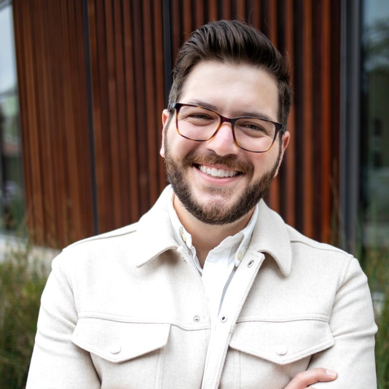 Smiling man with beard and glasses wearing cream button-up shirt