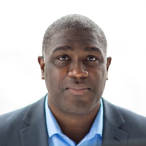Professional headshot of man in suit and light blue shirt against white background