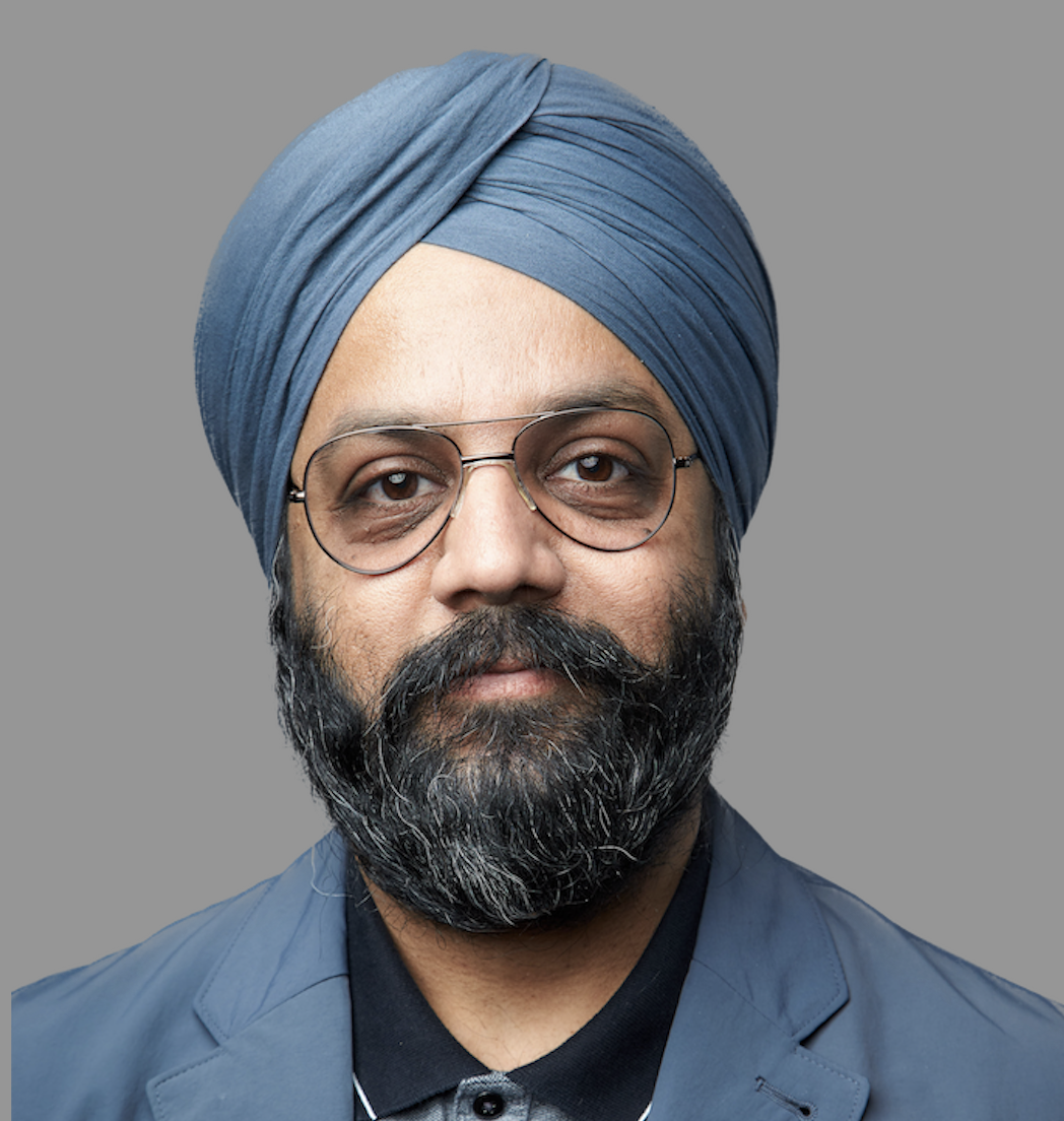 Man wearing blue turban and glasses with full dark beard, professional headshot