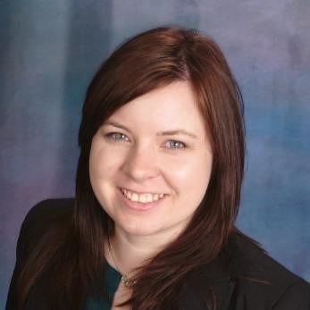 Portrait of a smiling woman with long brown hair wearing a black jacket