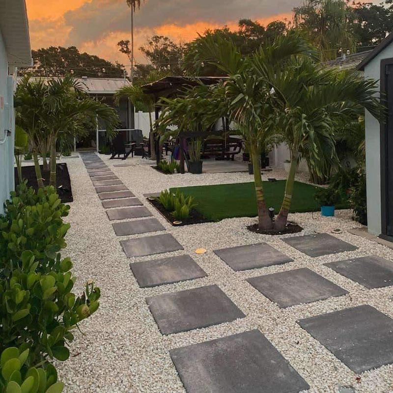 after backyard landscape design with paver walkway, gravel, and tropical plants for outdoor living space in Tampa Bay