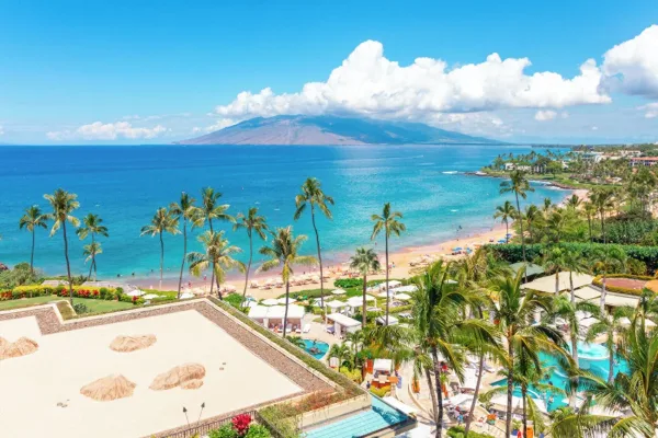 Four Seasons Resort Maui pools and cabanas above Wailea Beach, with the West Maui mountains across the water