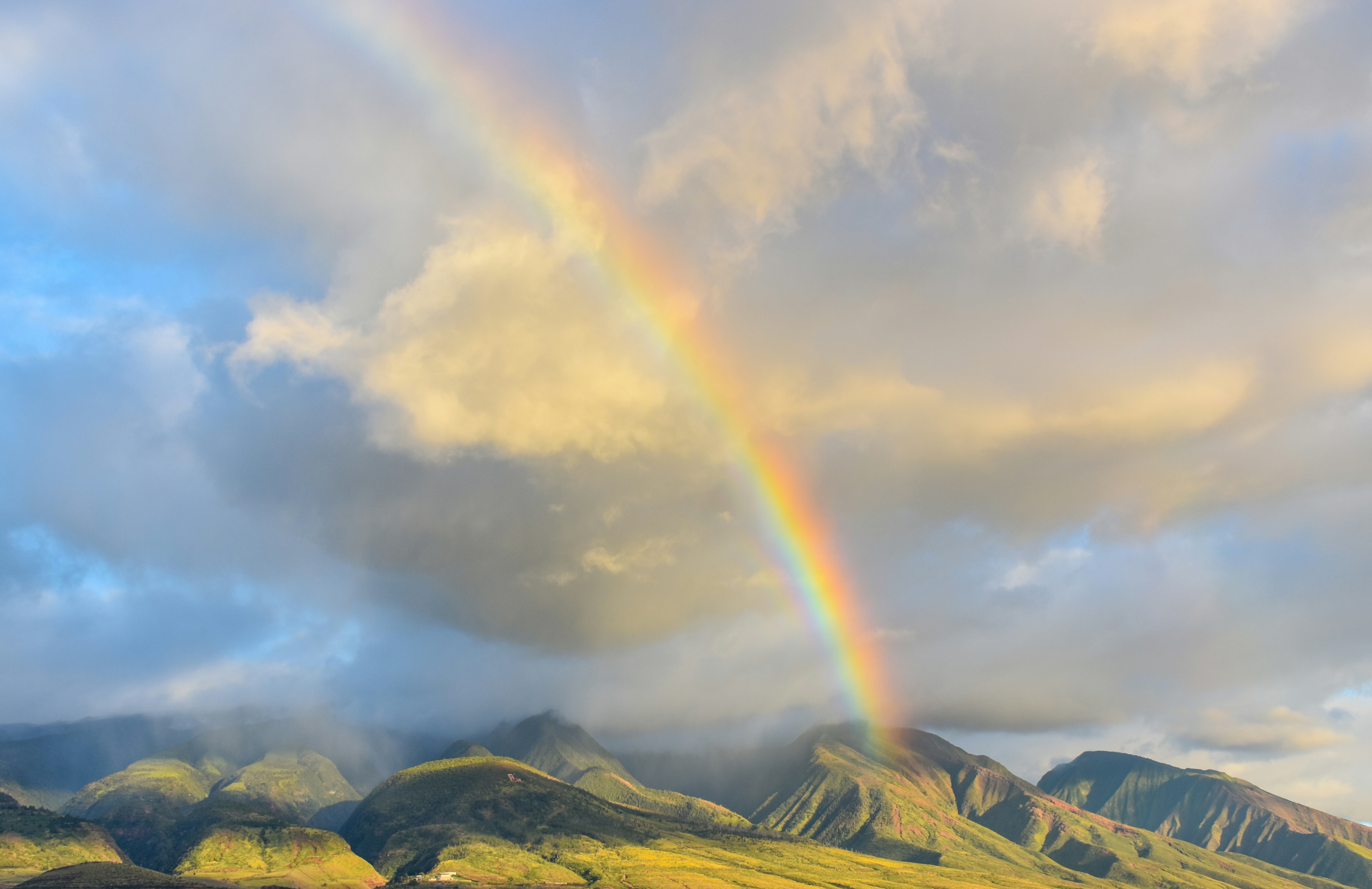 Rainbow arcing over the West Maui Mountains through breaking rain clouds