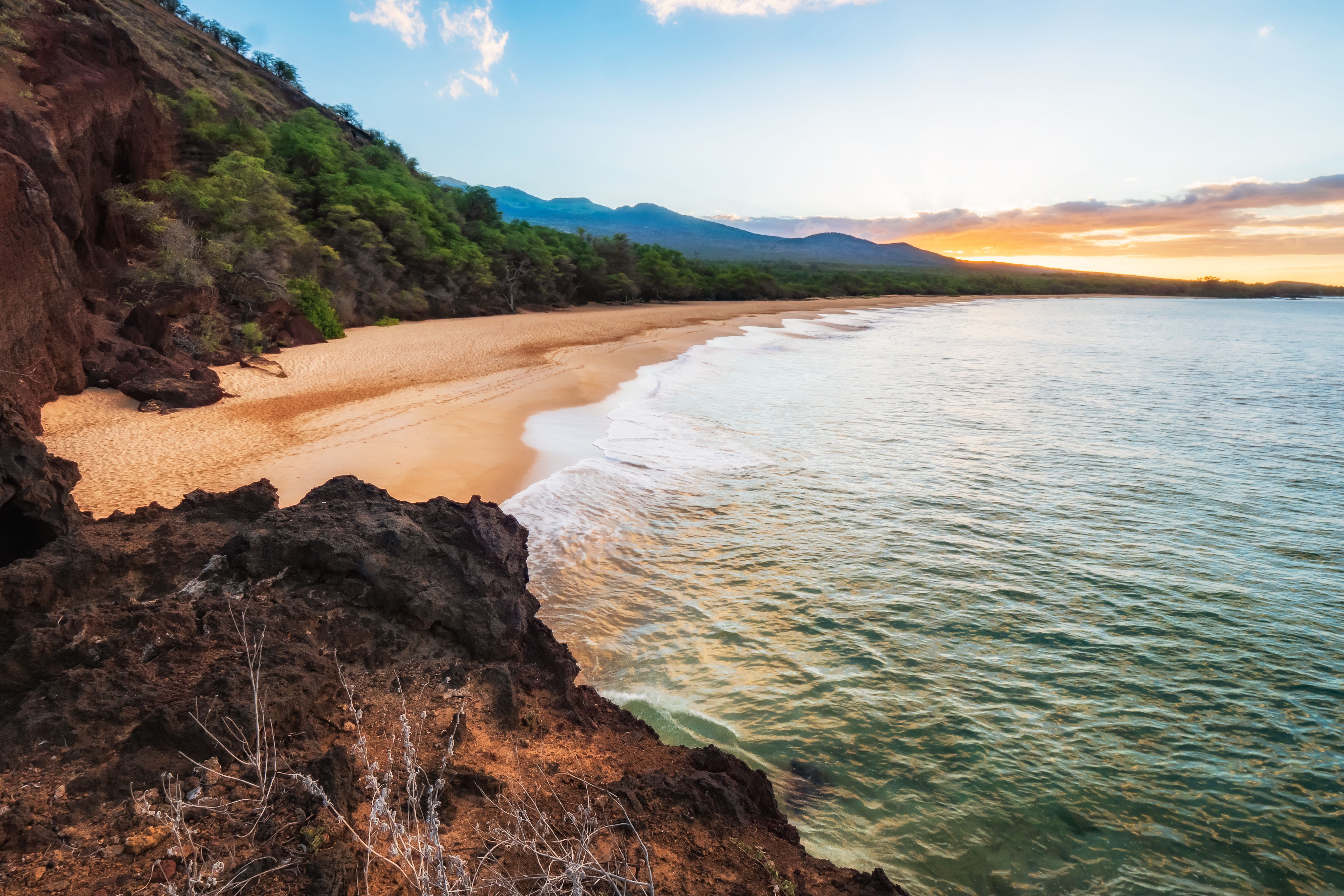 Makena Big Beach curving between lava rock and the ocean at golden hour