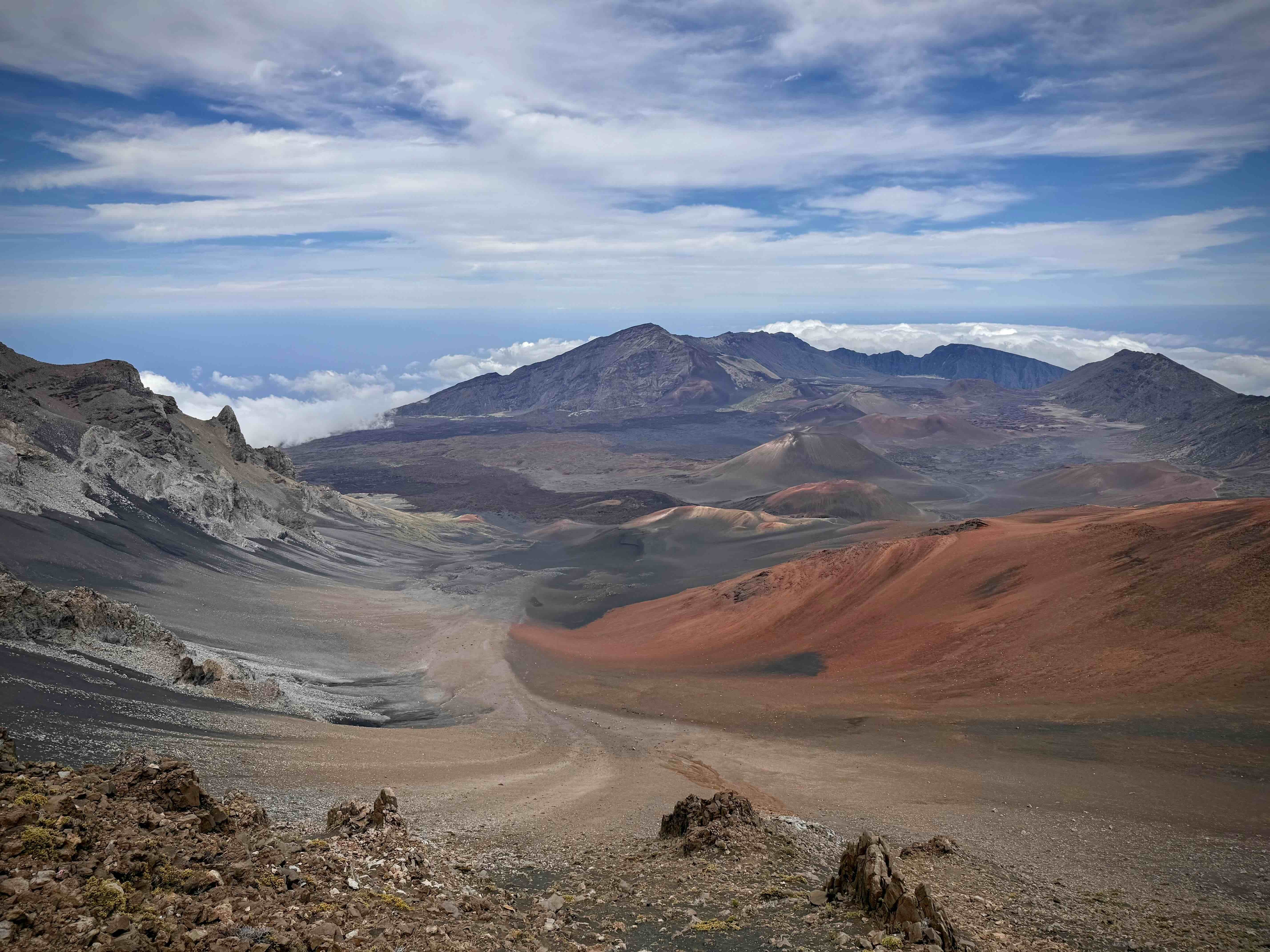 The Haleakalā crater floor seen from the rim, with red and grey cinder cones and the Sliding Sands trail descending across it