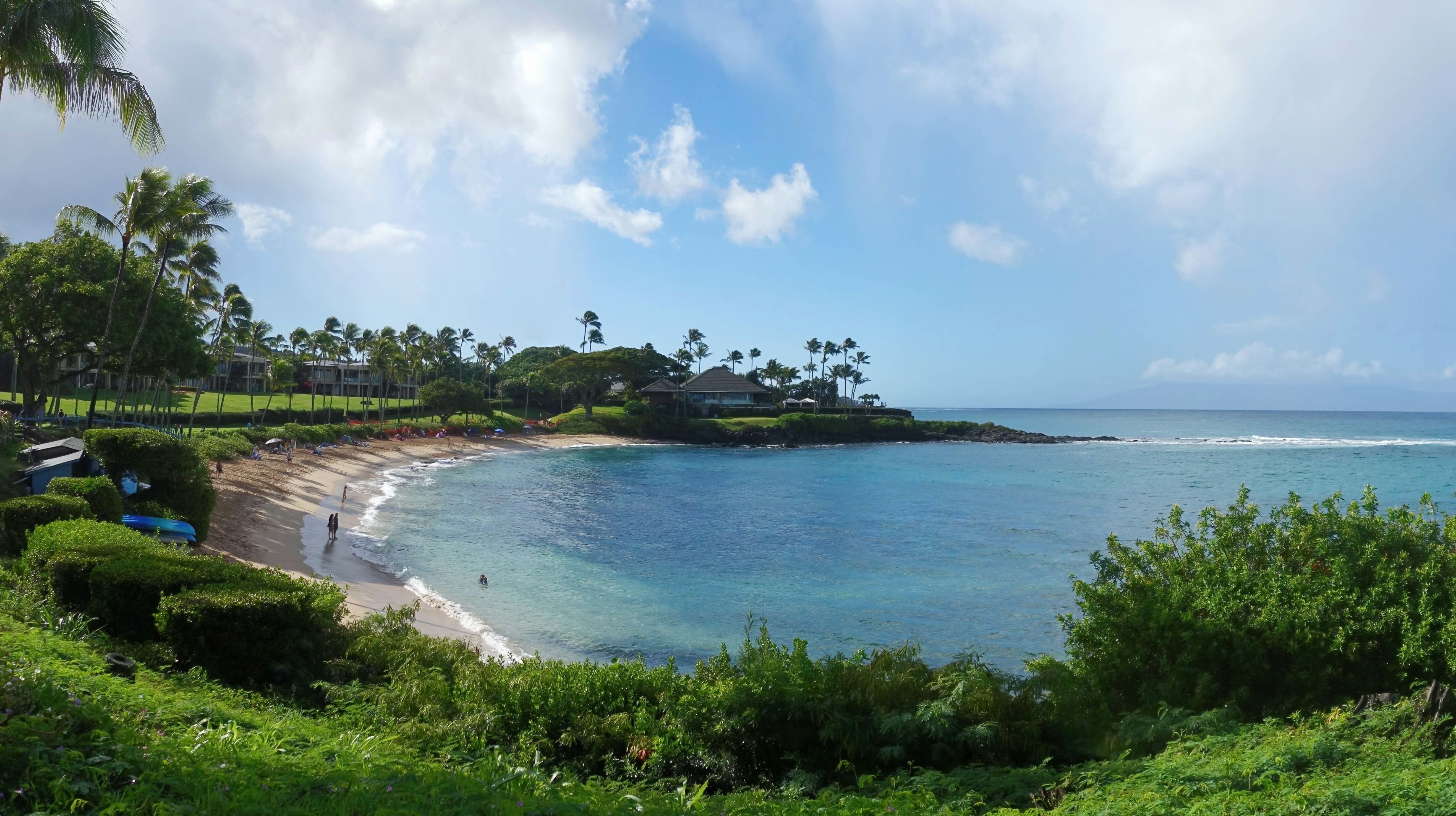 A small sheltered cove in Wailea, calm water inside a reef-framed bay with resort lawns behind