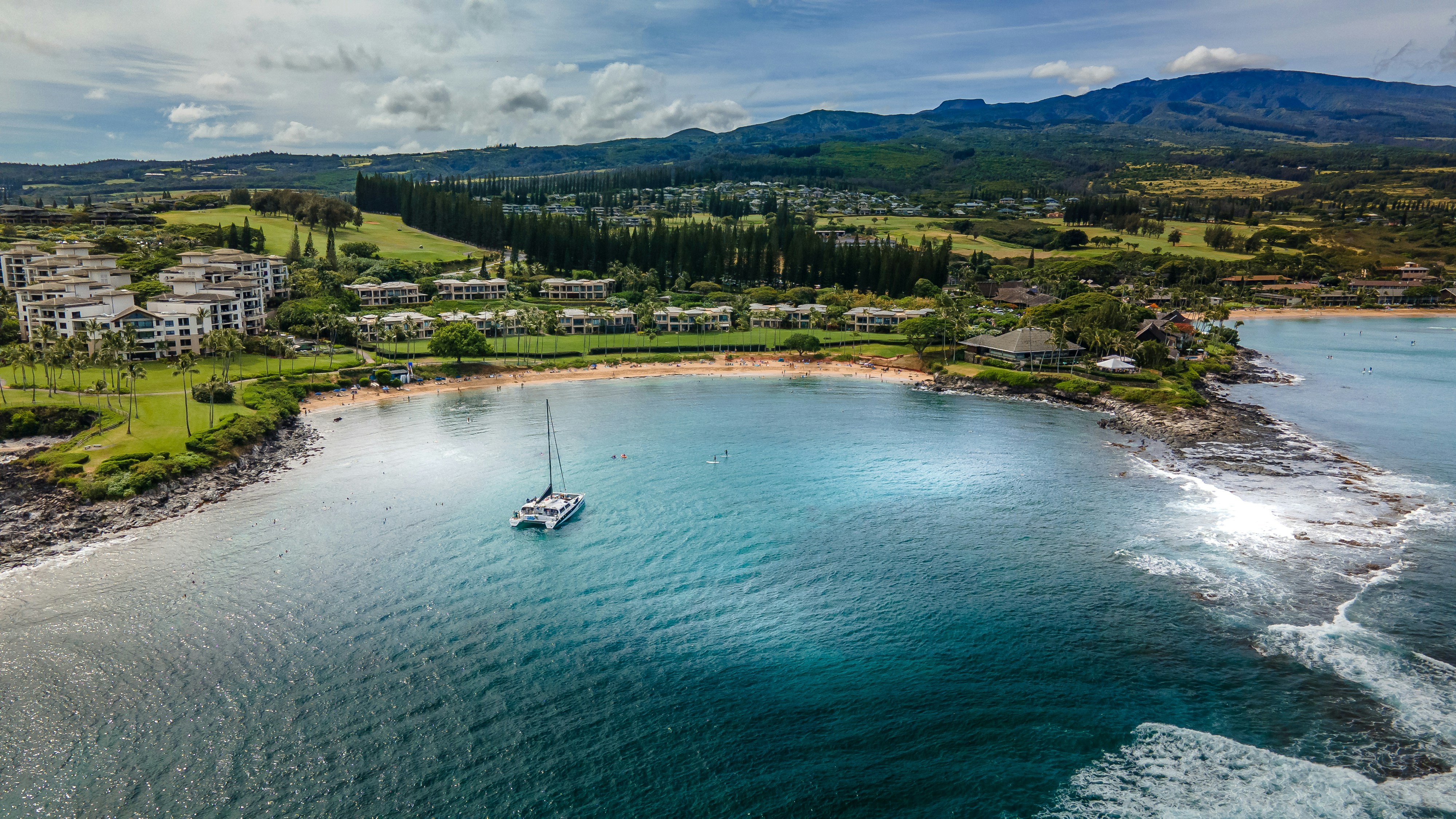Kapalua Bay from the air, a catamaran anchored in the sheltered bay with the resort behind