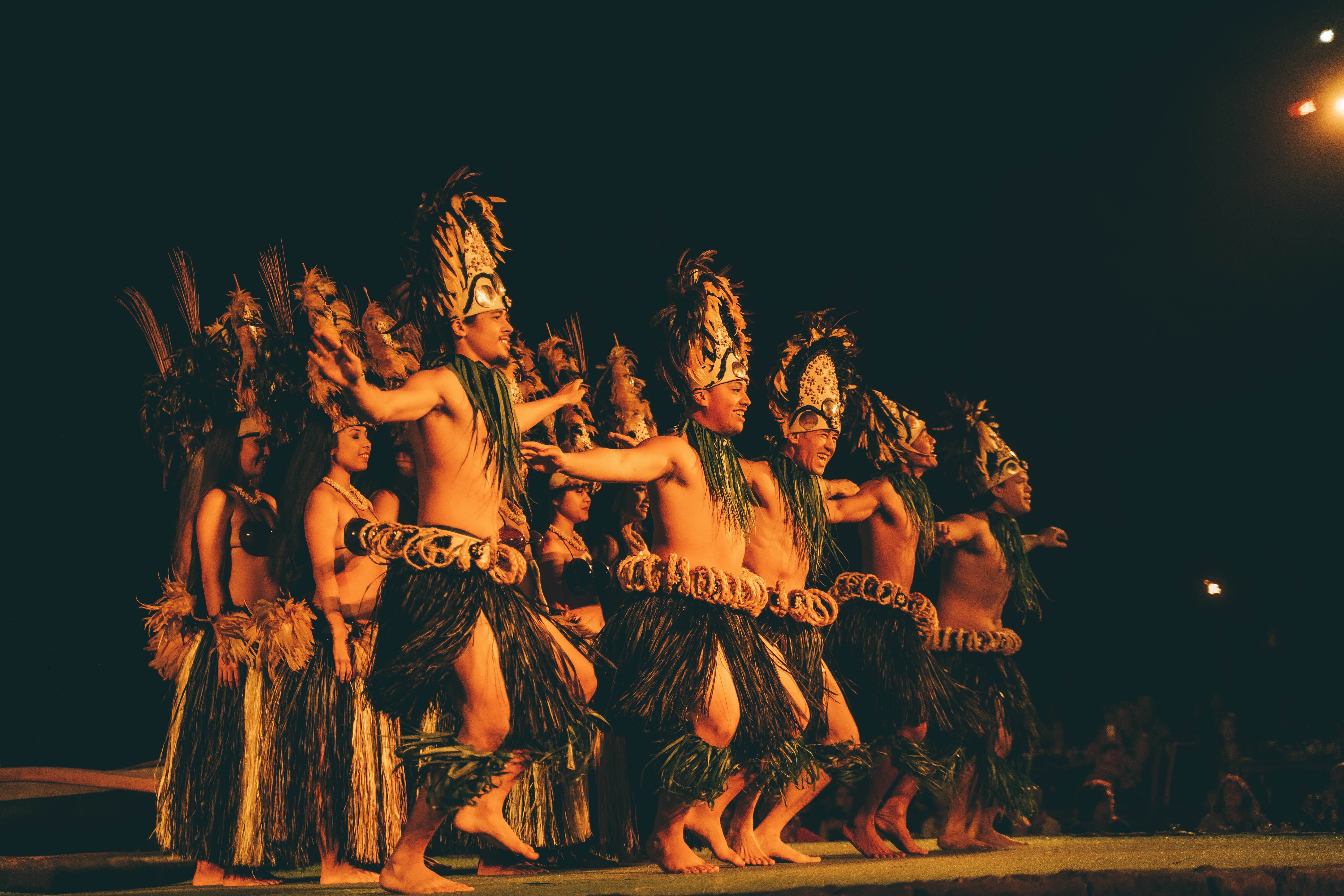 Hula dancers performing in a line on a lit stage at night
