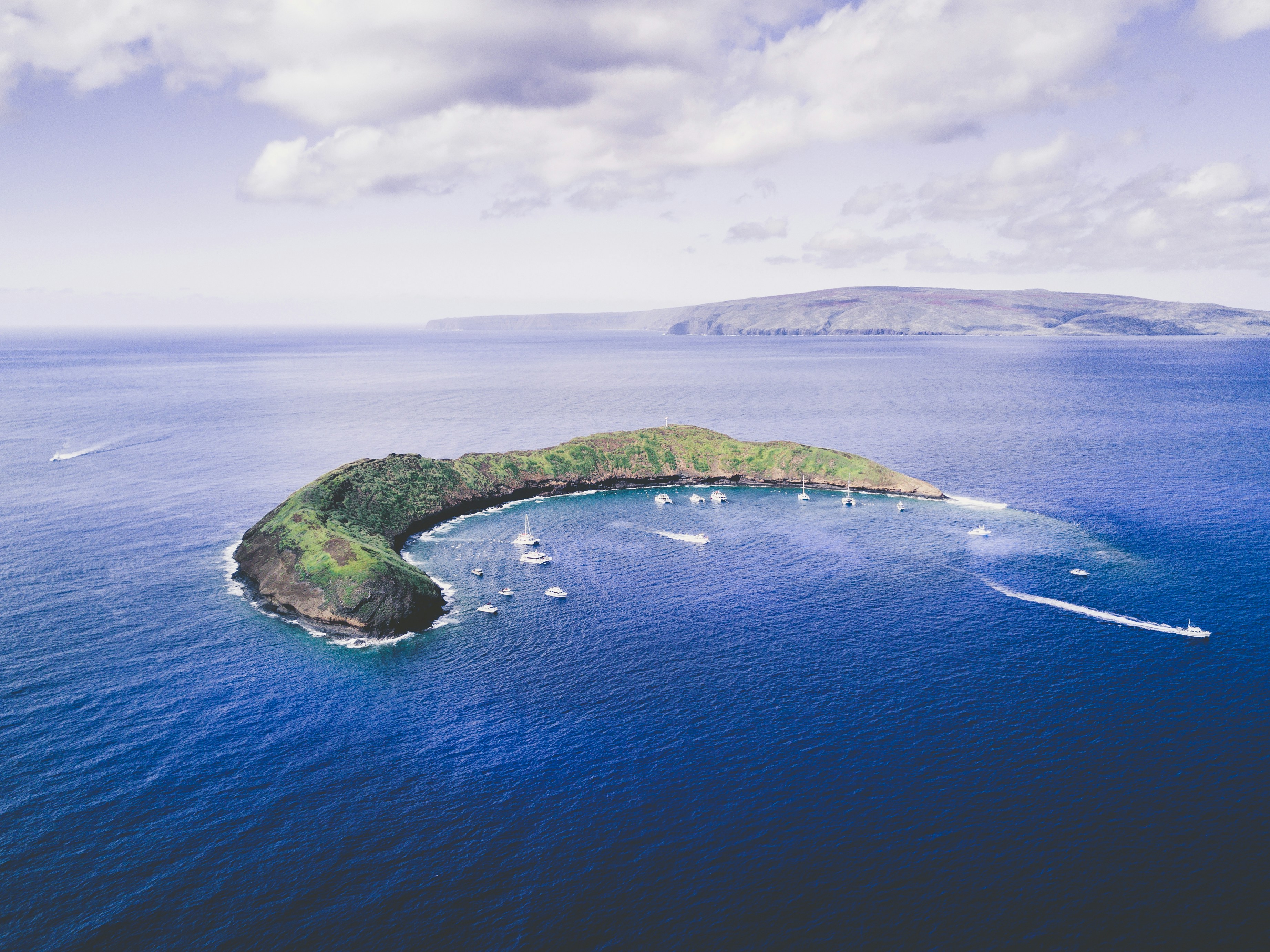 Molokini crater from the air, a crescent of rock in deep blue open ocean