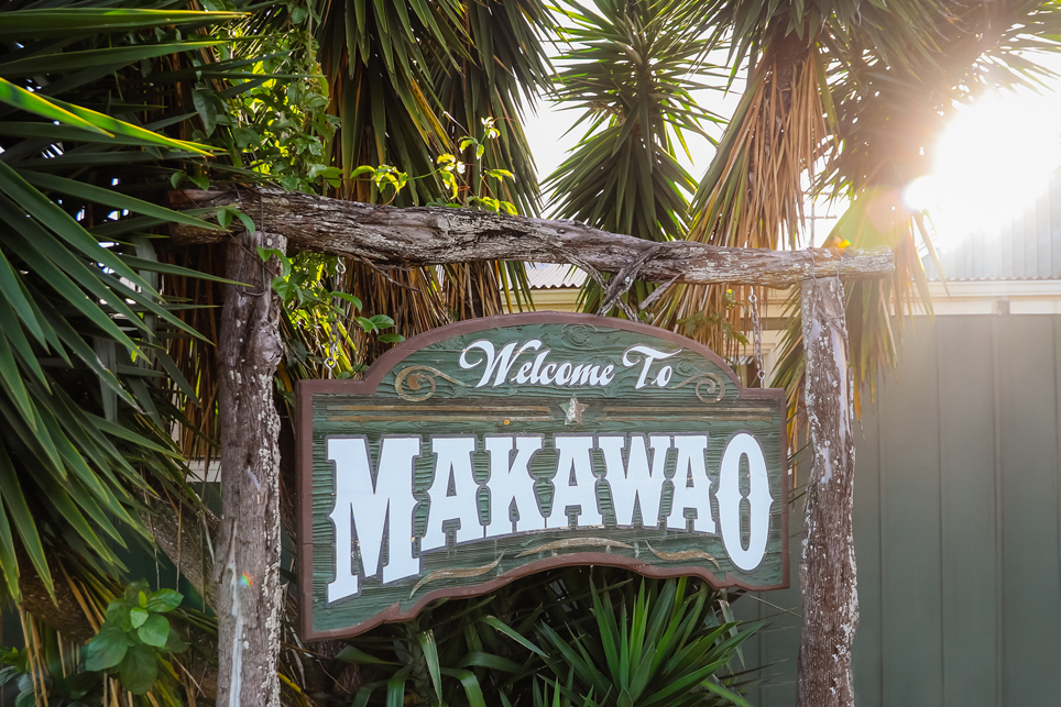 The painted Makawao town sign on a post beside an Upcountry road