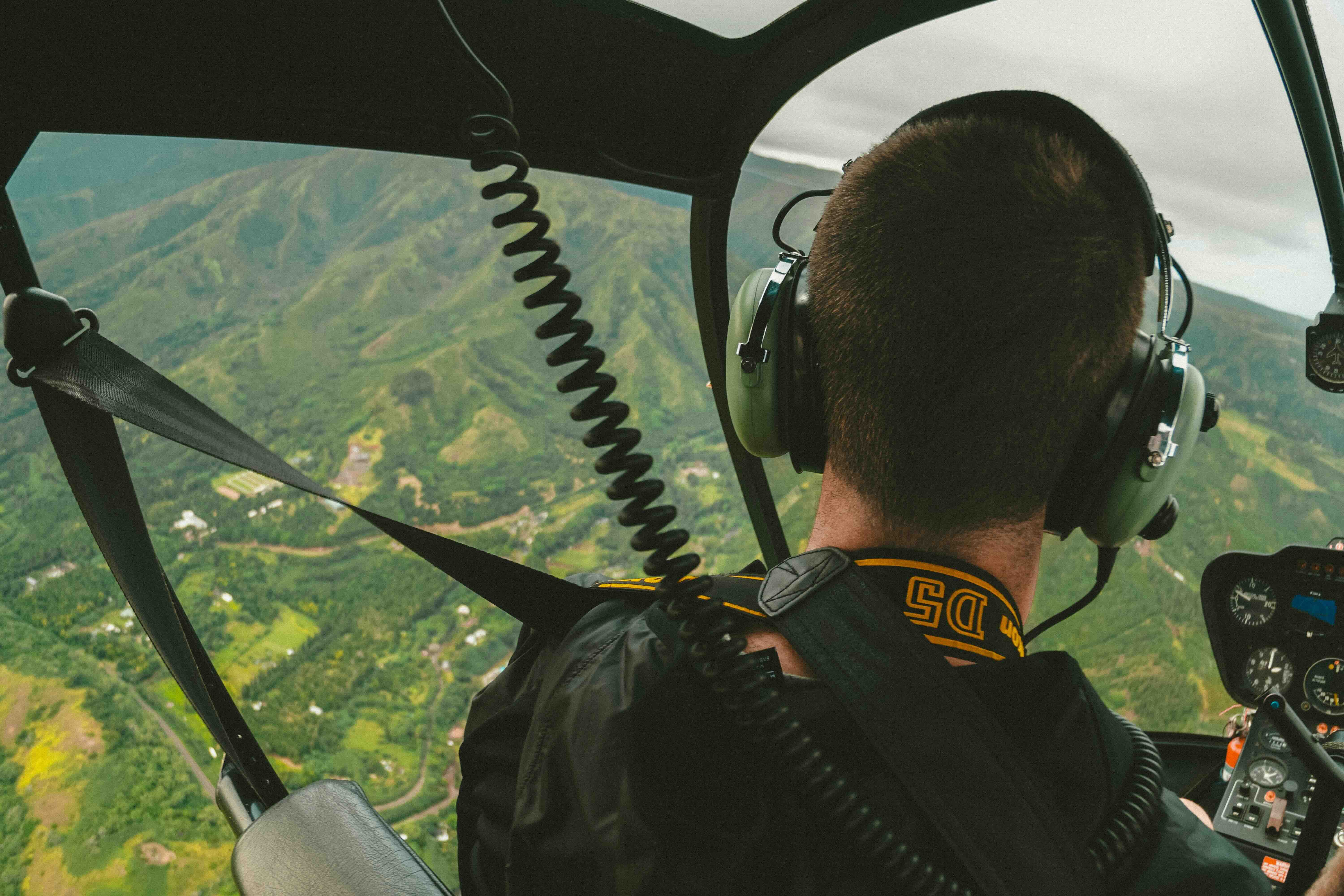A tour helicopter in flight above a green Maui valley