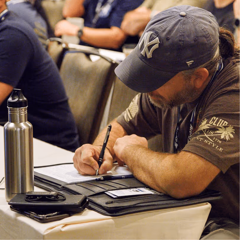 K-9 handler in a conference seminar session writing detailed training notes at his desk