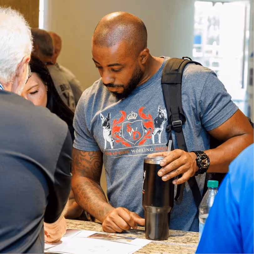 K-9 handler in a working dogs crest t-shirt reviewing registration materials at the HITS conference check-in table