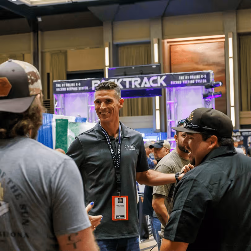 K-9 training professional smiling while connecting with fellow handlers at the HITS conference vendor expo hall