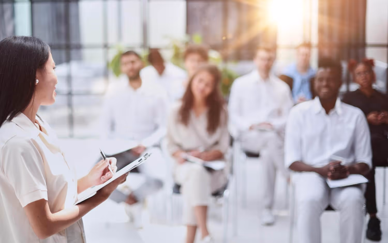 Health educator speaking to a diverse group of adults seated in a bright room taking notes.
