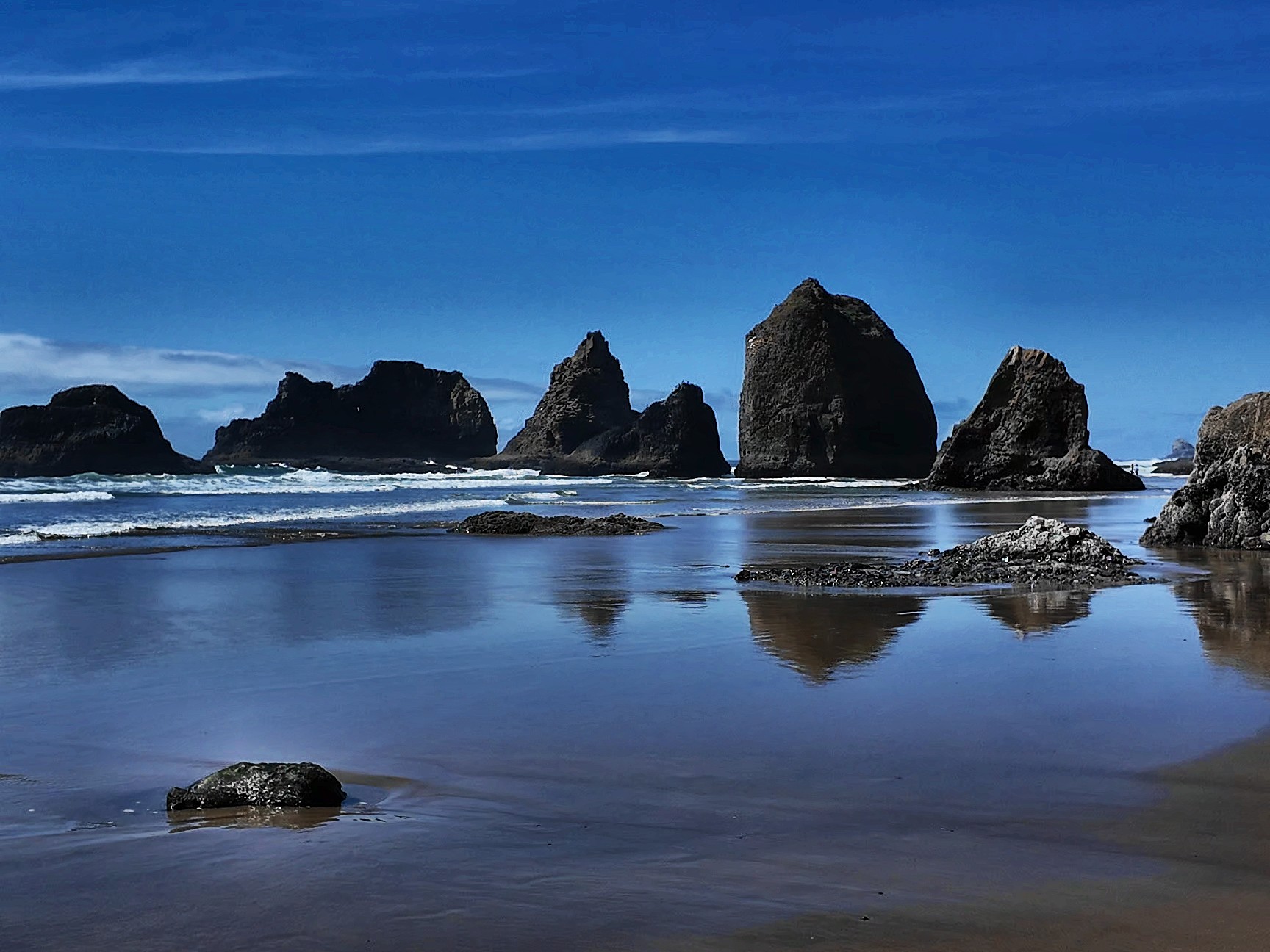 Sea stacks reflected on wet sand at low tide on the Oregon coast