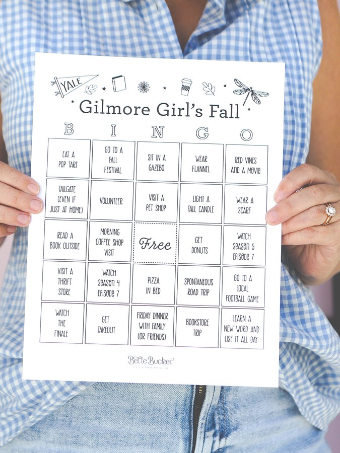 Gilmore Girls Fall bingo card printable, held up in front of a pink door