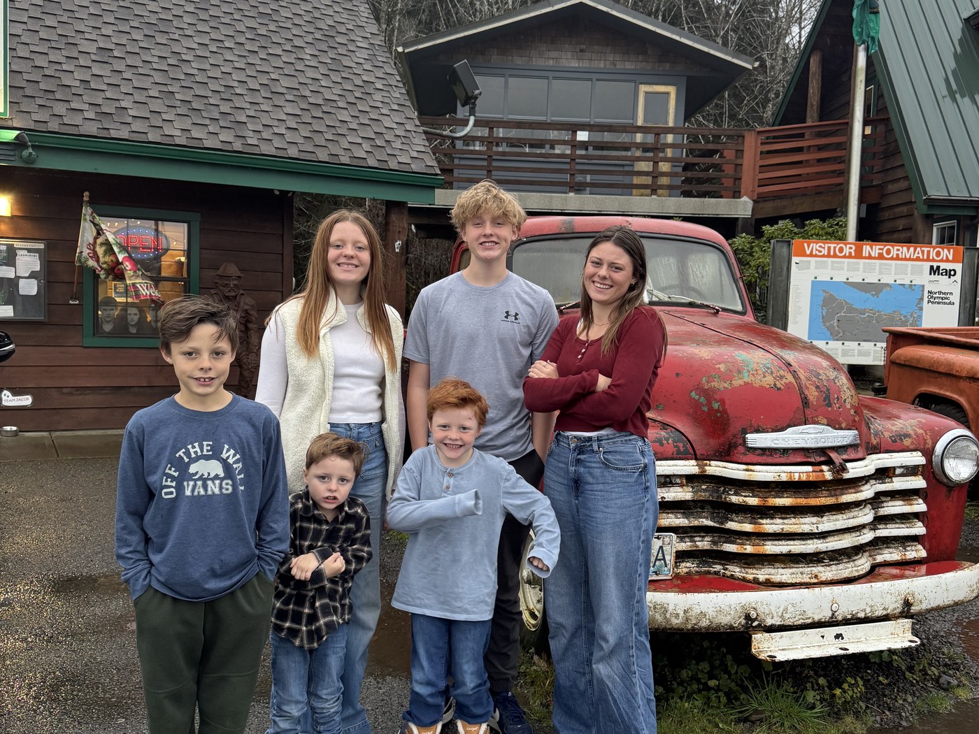 Amy and the kids with Bella's red truck outside the Forks Visitor Center in the rain