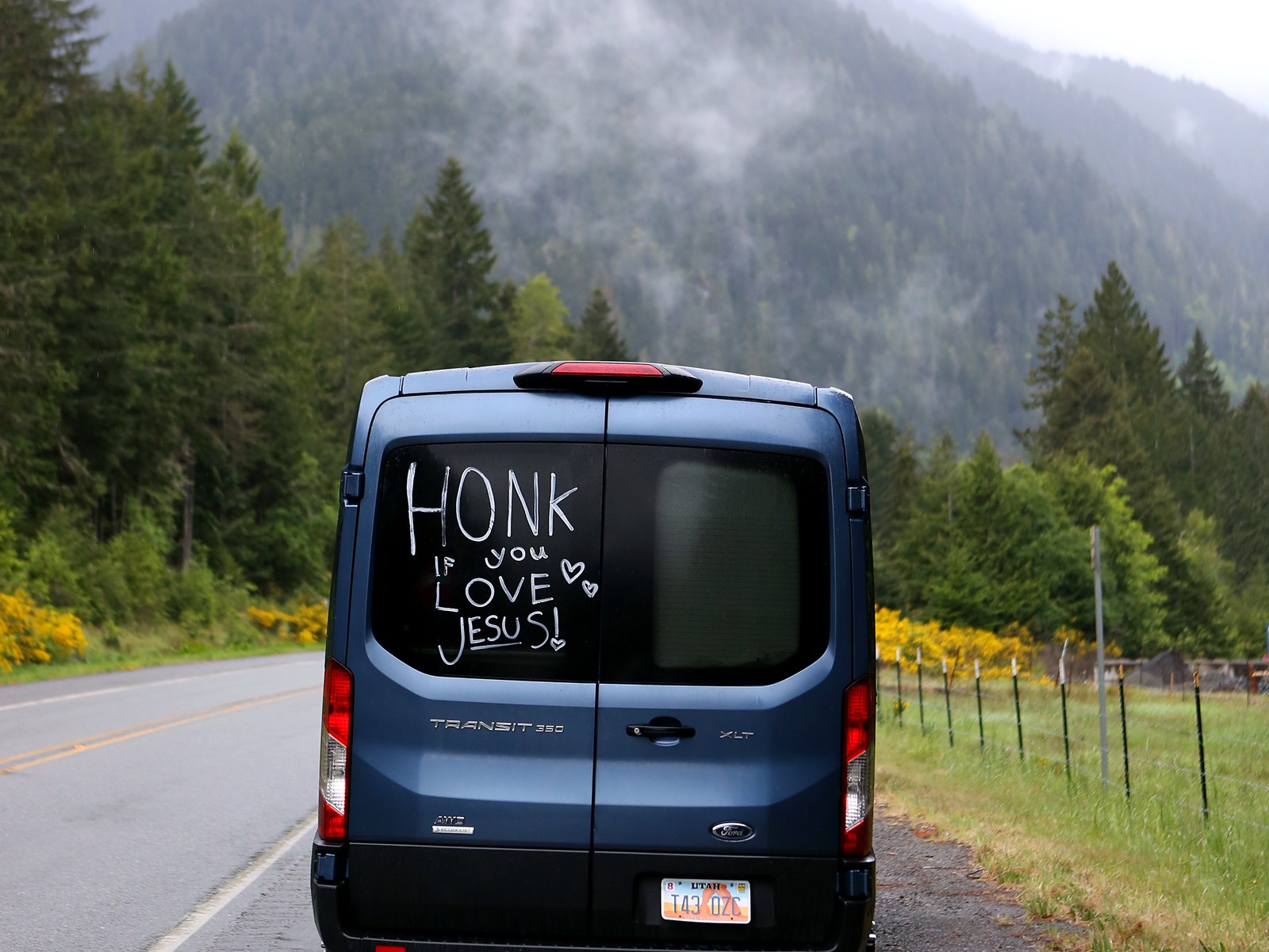 The back of our blue Ford Transit van on US-101 with fog on the mountains behind