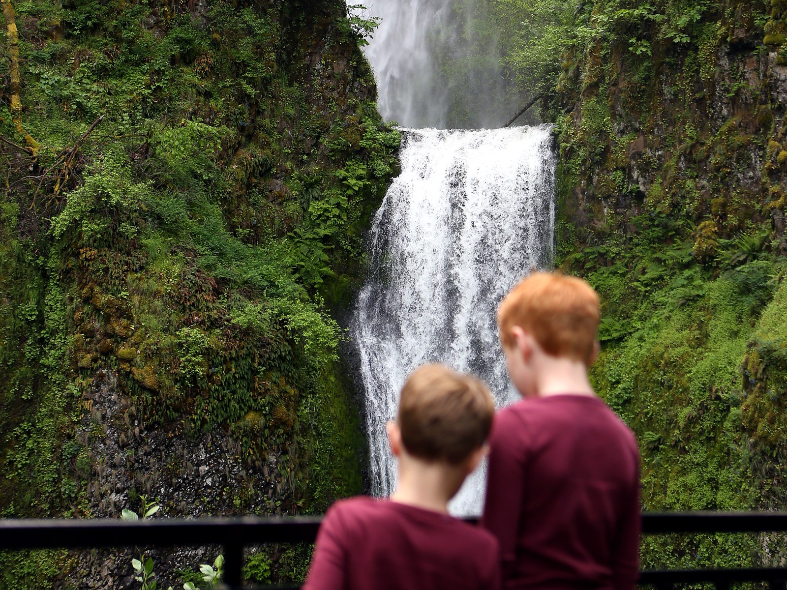 Two of the boys at the rail looking up at Multnomah Falls