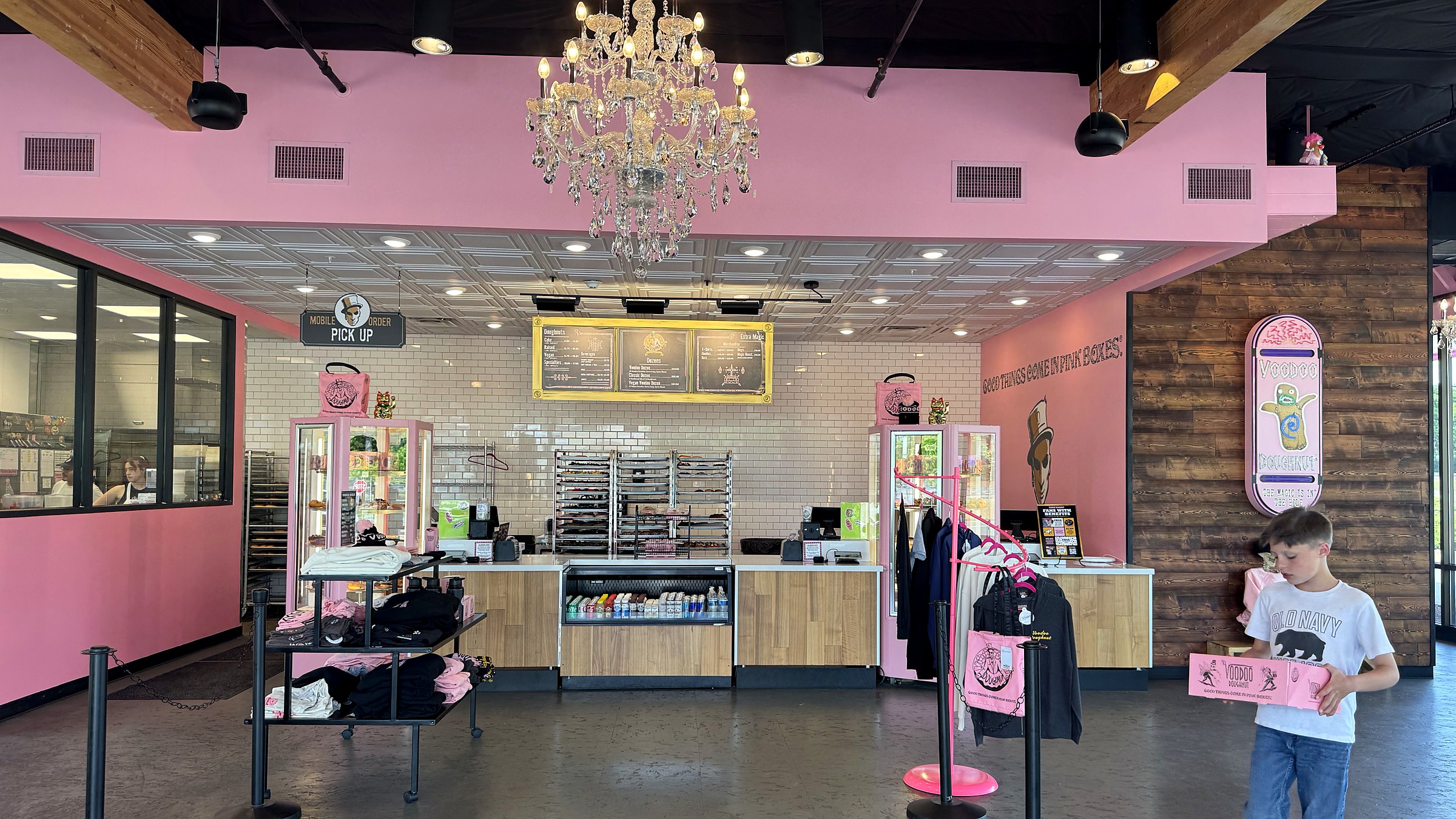 Inside Voodoo Doughnut, pink walls and a chandelier, one of the boys headed out with the box