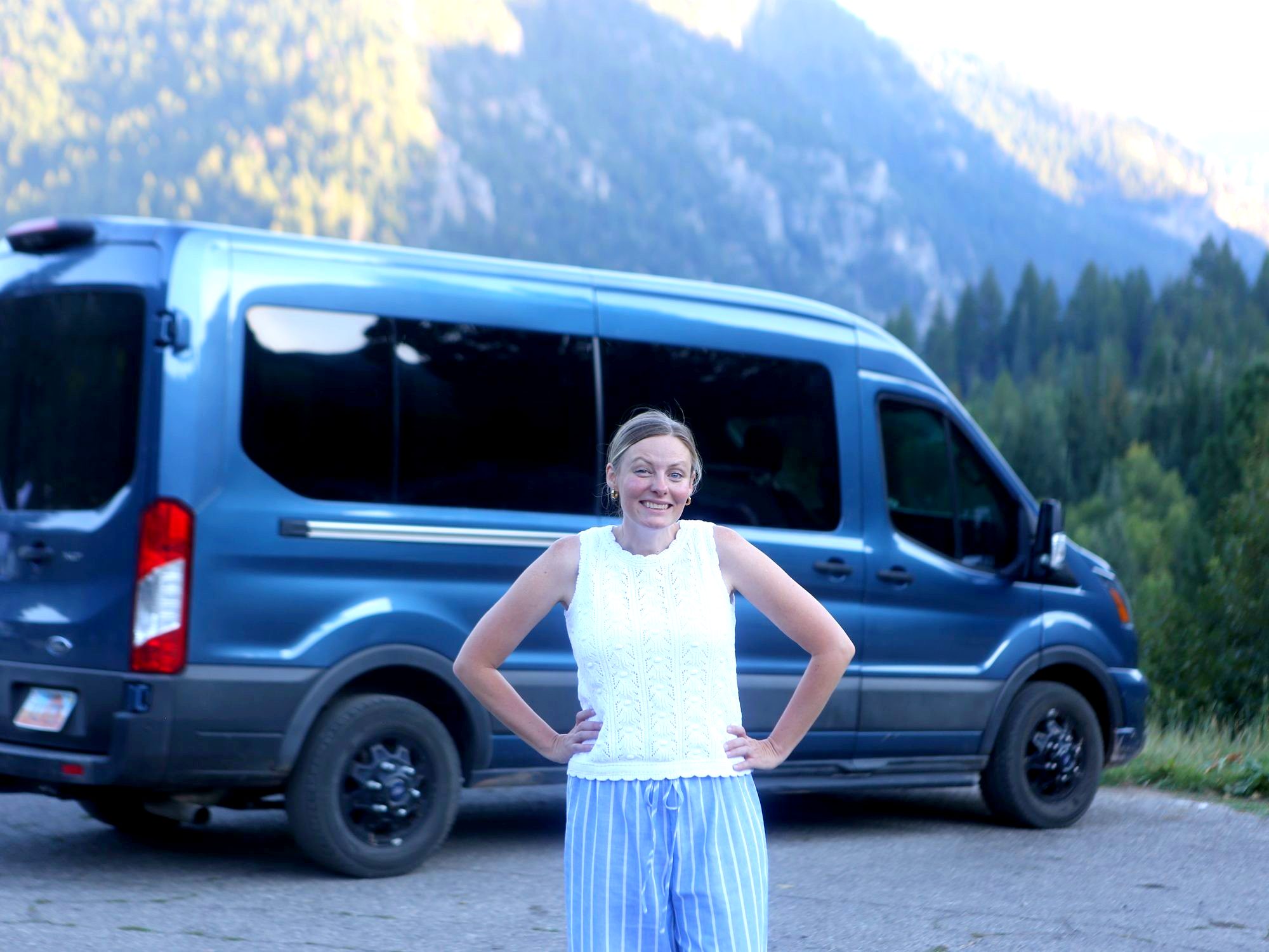 Amy standing in front of the big blue van with the mountains behind
