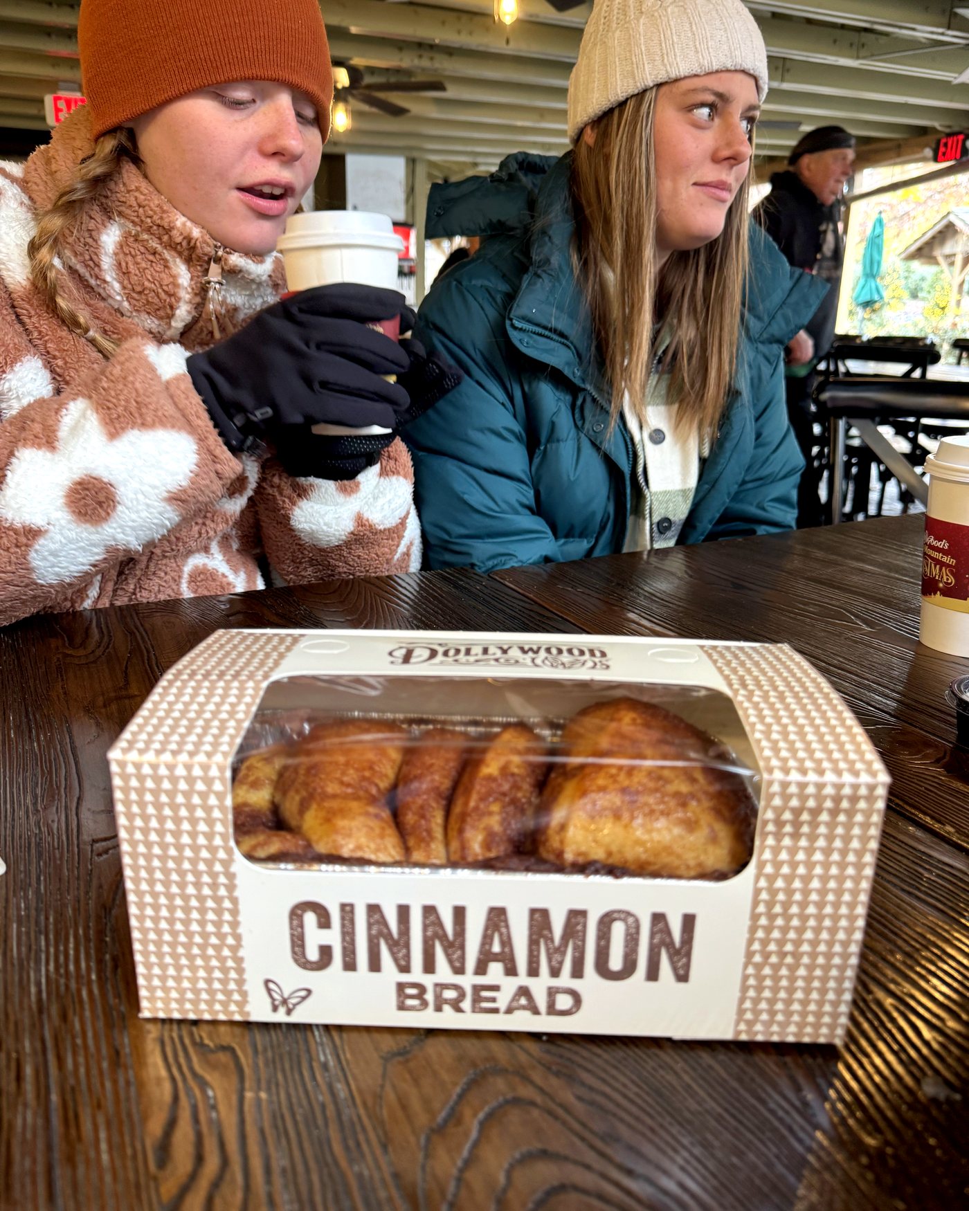 Two of the girls at a table at Dollywood with a box of the Grist Mill cinnamon bread