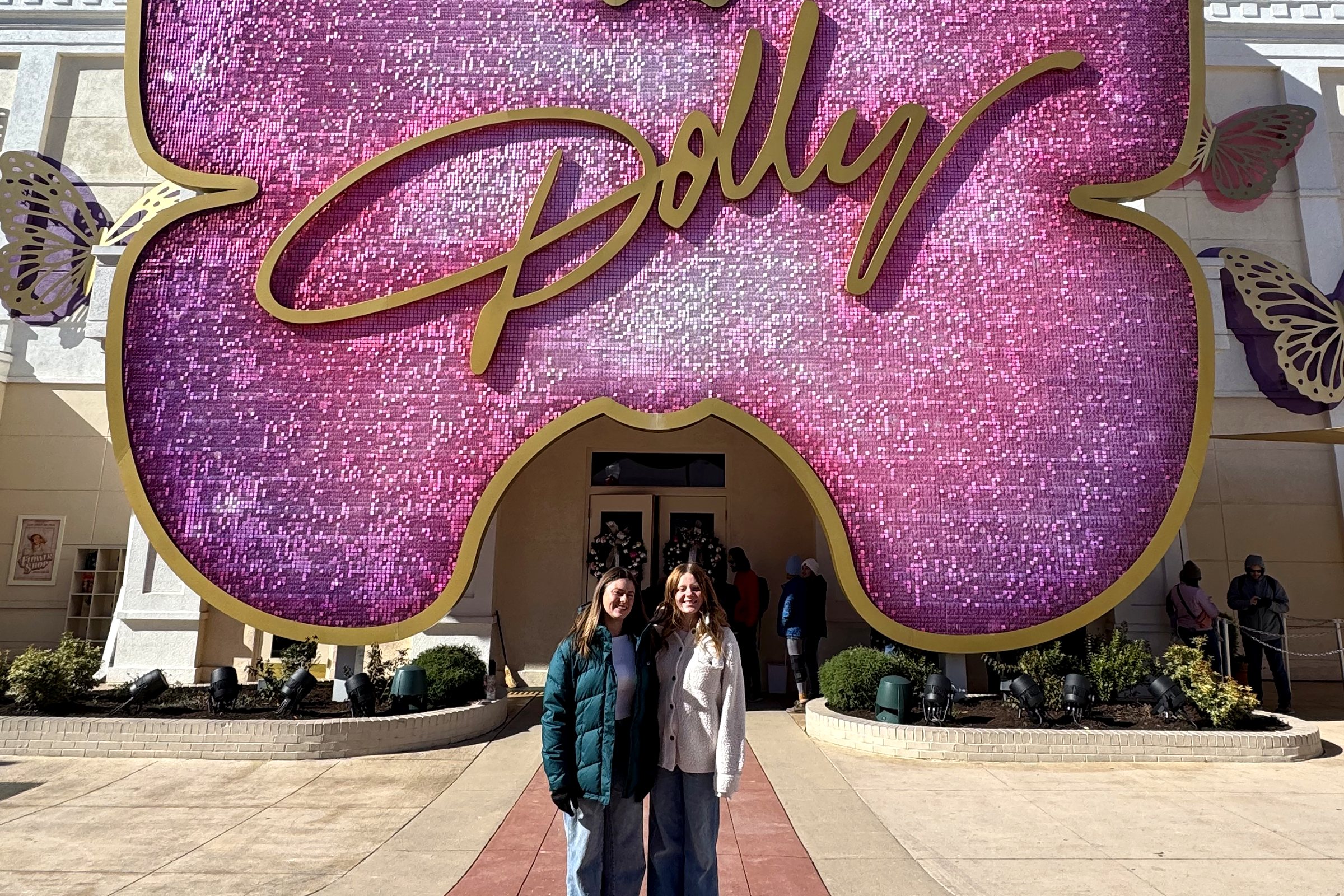Two of the girls under the giant pink Dolly butterfly sign at Dollywood