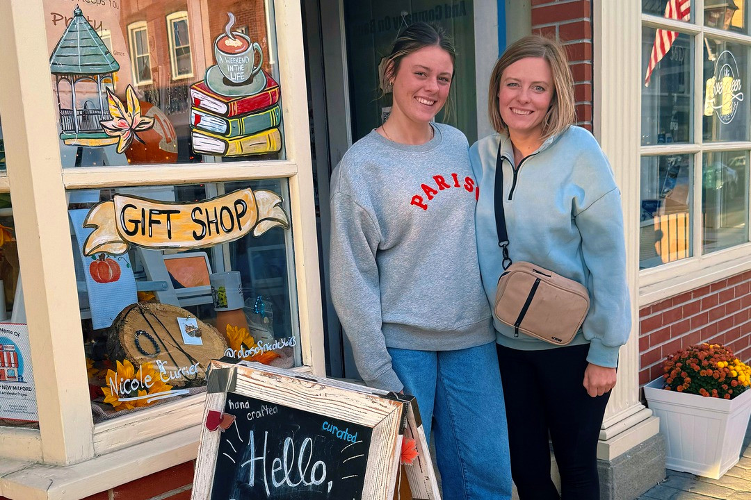 Amy and one of the girls outside a little gift shop, a Hello Sunshine chalkboard out front and fall leaves painted on the window