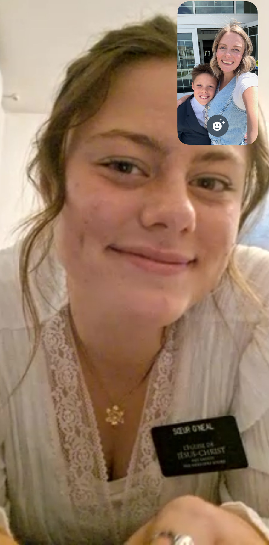A FaceTime screenshot of Lily in her missionary name tag, smiling, with Amy and one of the boys in the little window in the corner